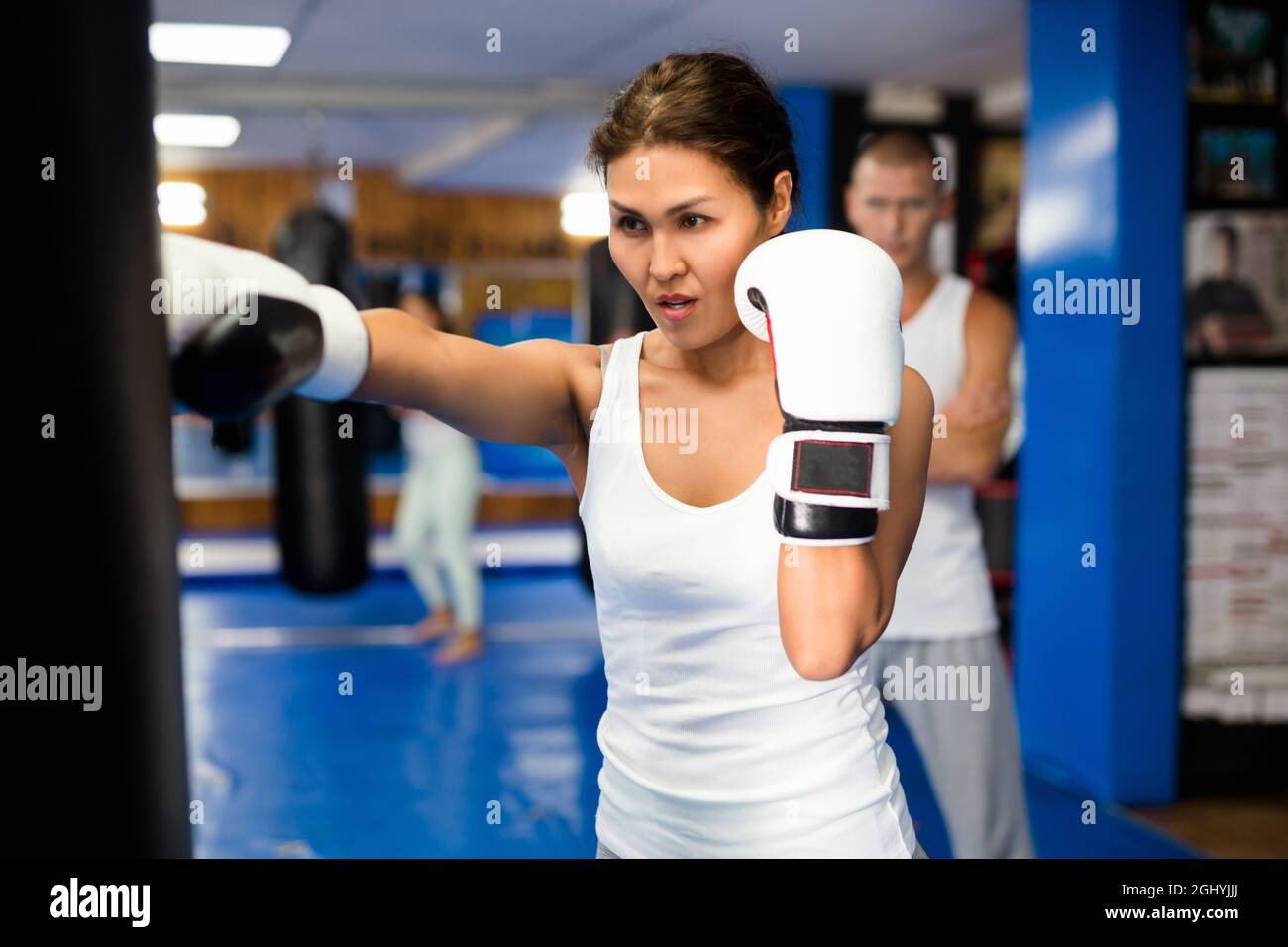 Asian female practicing punches with boxing bag at gym Stock Photo