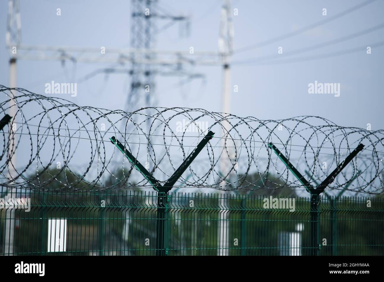 Barbed wire, strictly guarded object against the background of the power line Stock Photo