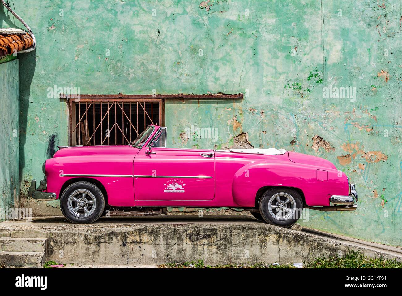 parkender Oldtimer vor einer verrottenden Wand. Ein tolles Farbenspiel in Havanna, Cuba Stock Photo
