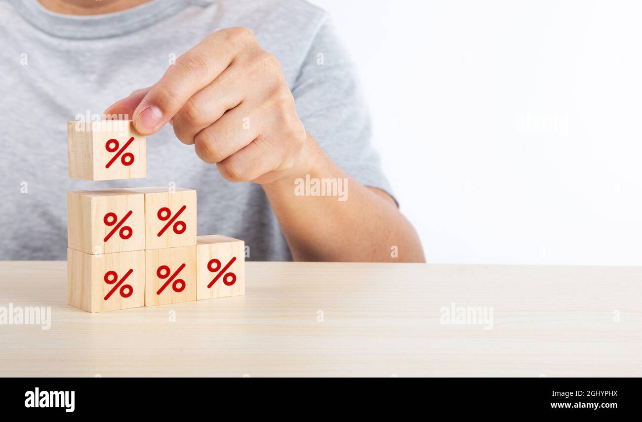 Interest rate financial and mortgage rates concept. Hand putting wood cube block increasing on top with icon percentage symbol upward direction Stock Photo