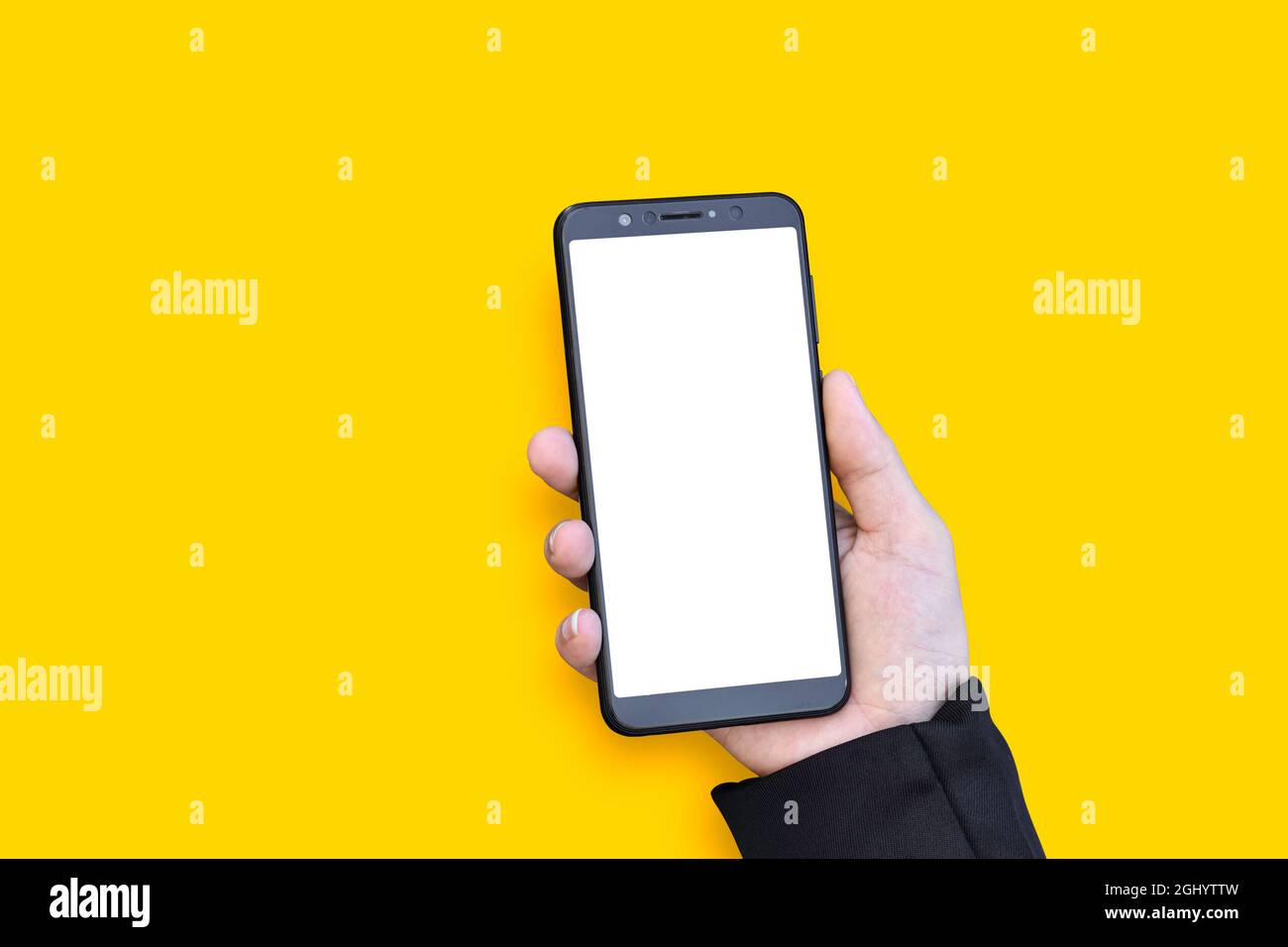 Hands hold mobile smartphone with blank screen on yellow background