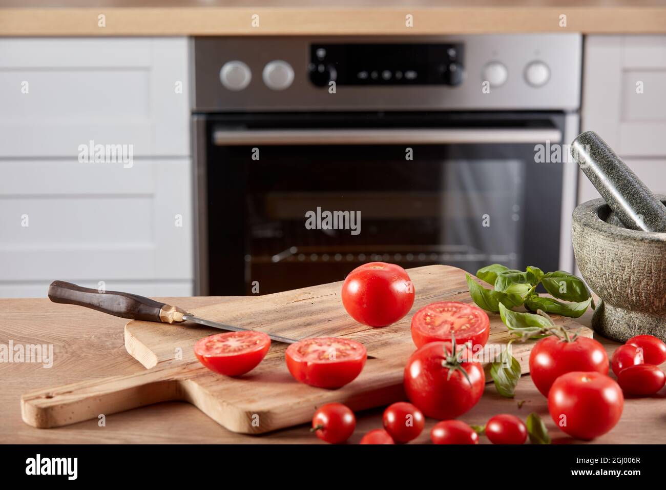 Fresh whole and halves of fresh tomatoes placed on wooden chopping ...