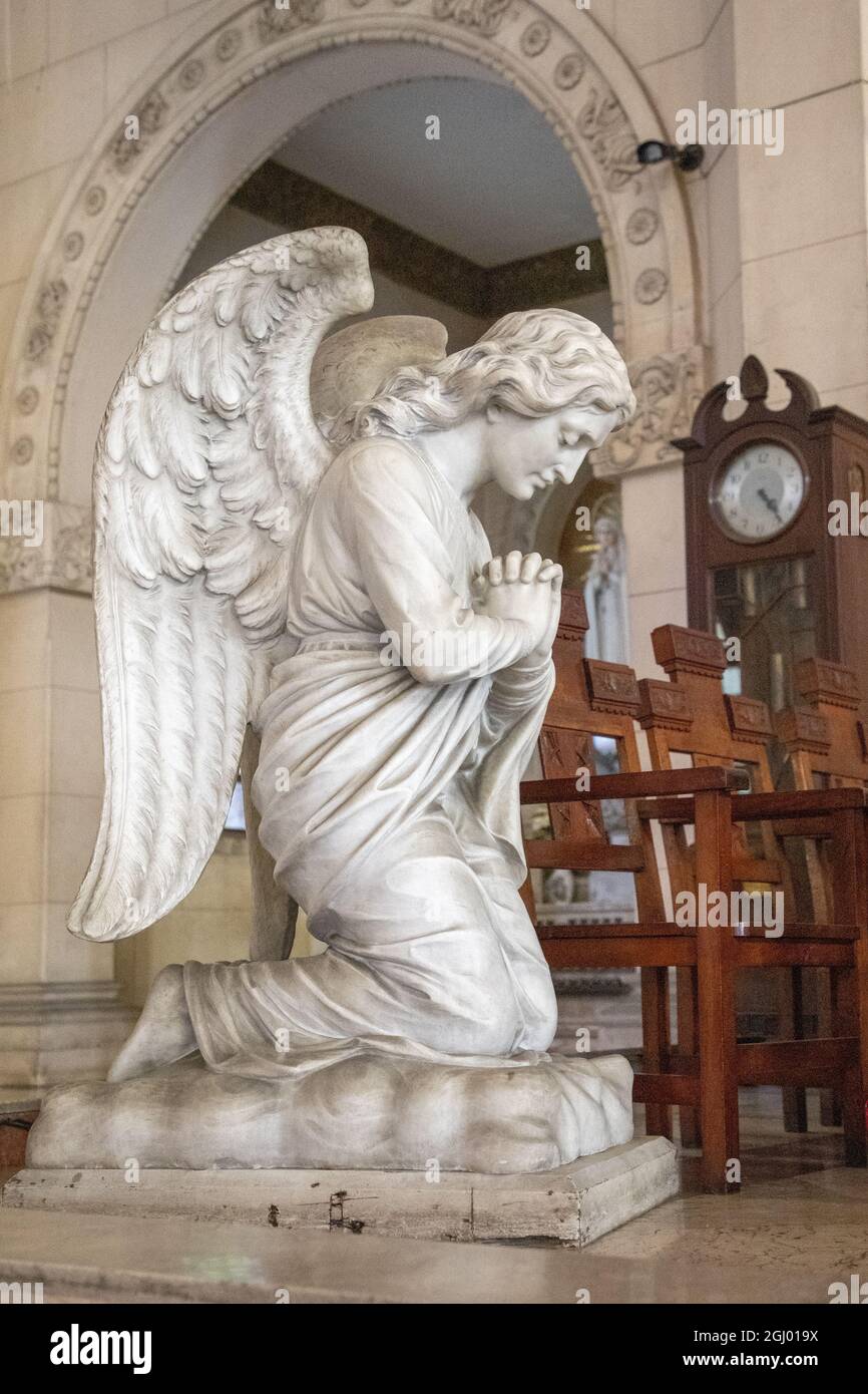Vertical shot of a kneeling angel statue inside a church Stock Photo