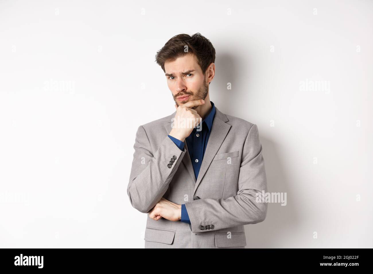 Hesitant To Report Hesitant young businessman in suit looking skeptical at camera ...