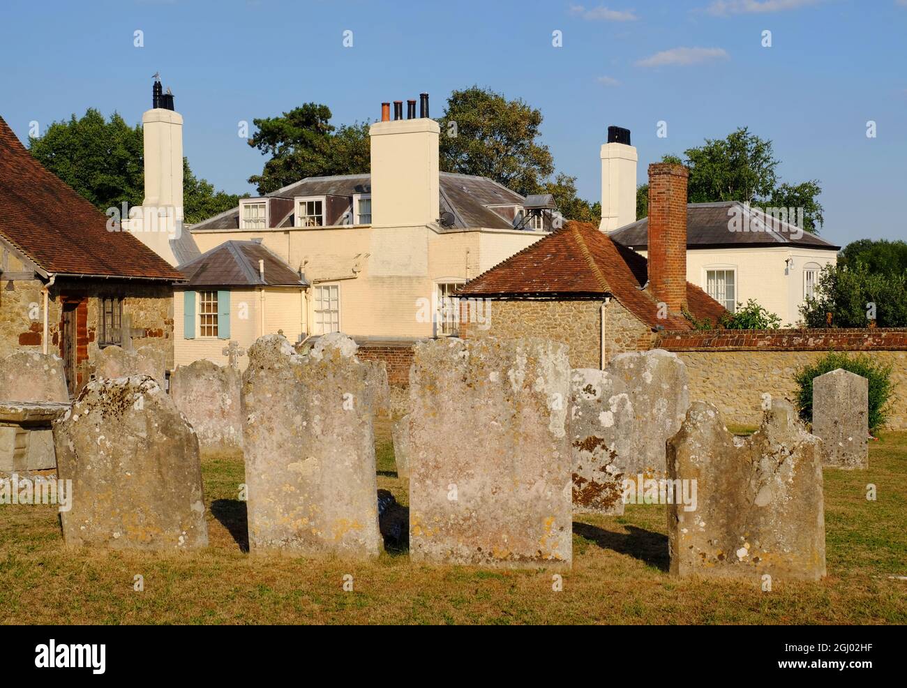 Gravestones in graveyard of Church of St Mary the Virgin and period house soon before sunset in West Malling, Kent, England Stock Photo