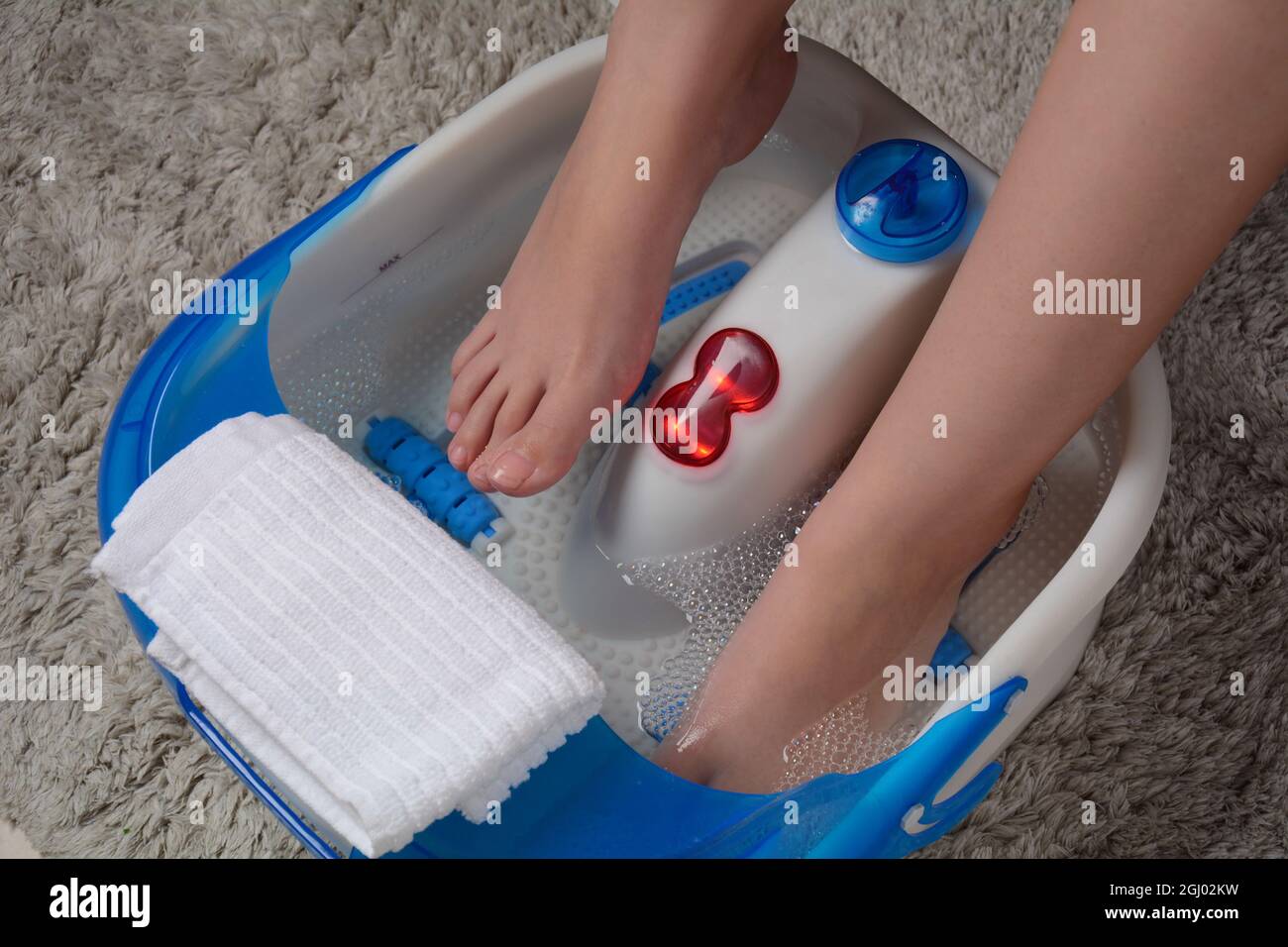 homedics pro therapy vibration neck massager Female feet in a vibrating foot massager. Electric massage foot bath. Relax  after work. Pedicure and foot care Stock Photo