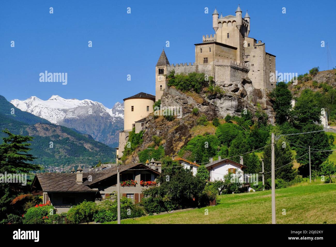 Snow covered mountains, Saint Pierre Castle, church and houses in Saint Pierre, Aosta Valley, Italy Stock Photo