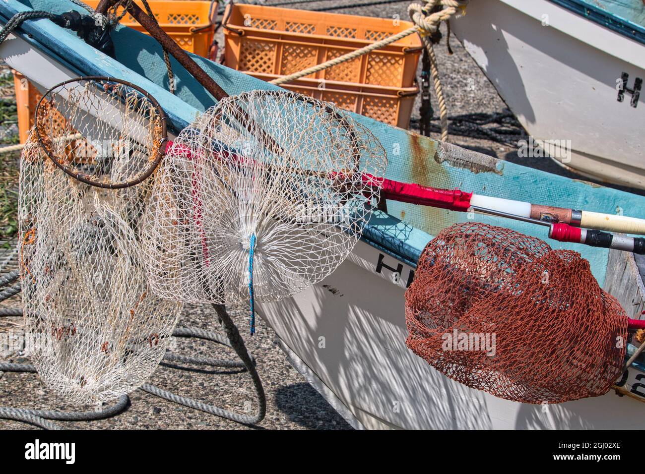 Three commercial landing nets used for fishing rest on a blue and white  boat Stock Photo - Alamy