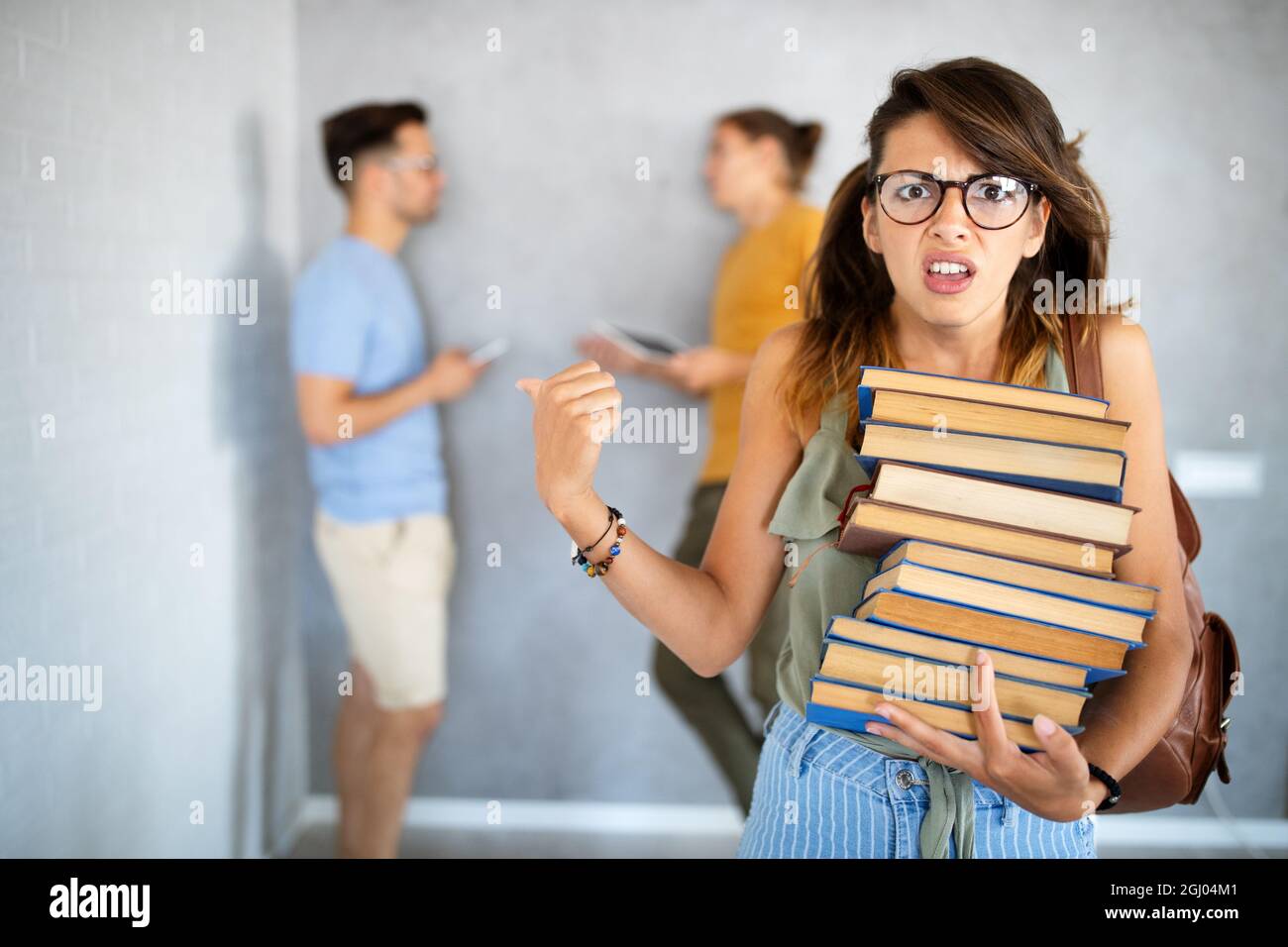 Unhappy student girl looking at her lazy mates who are playing with the phone instead of working Stock Photo