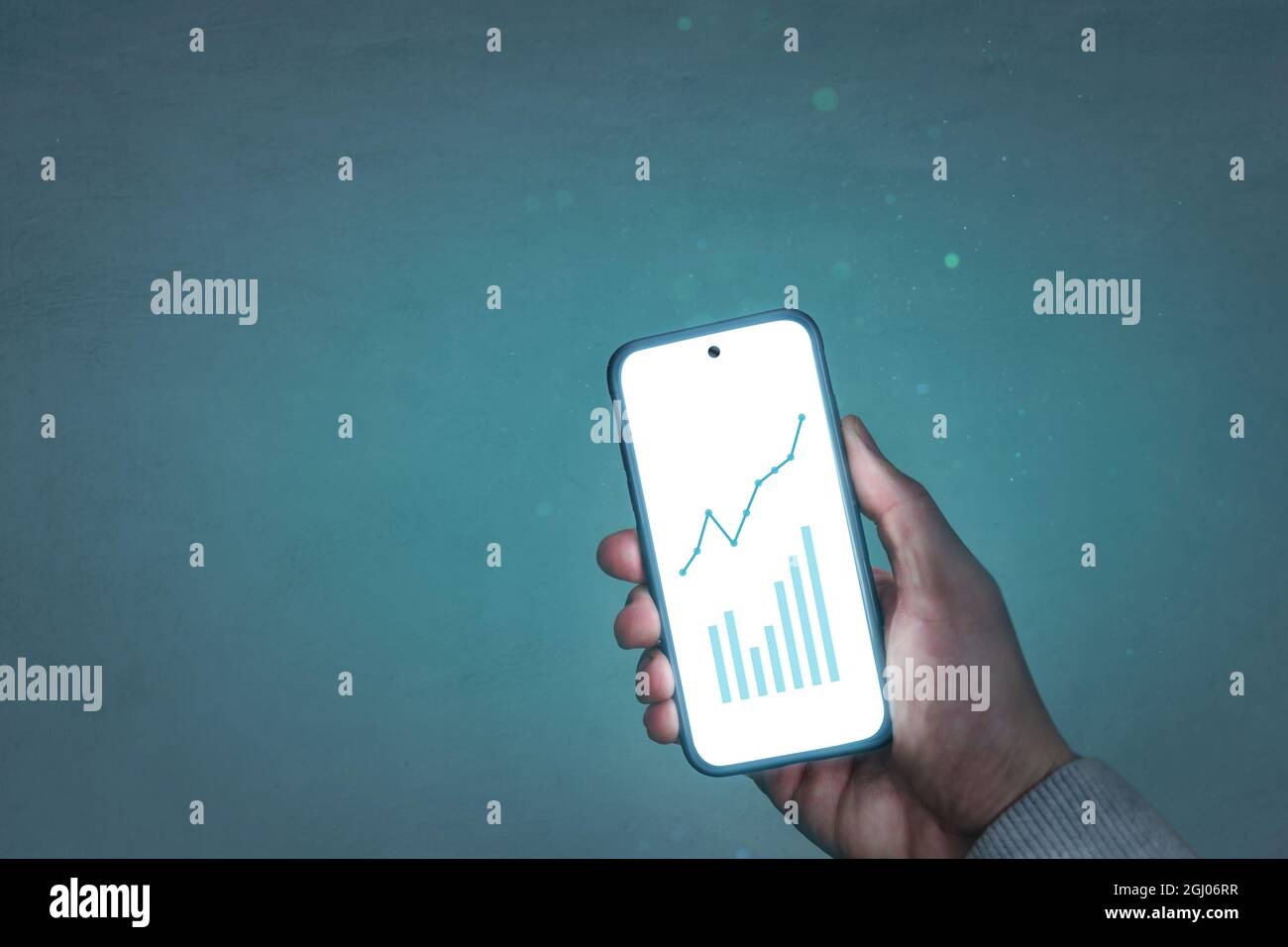 Hand holding a glowing smartphone with chart graphics Stock Photo