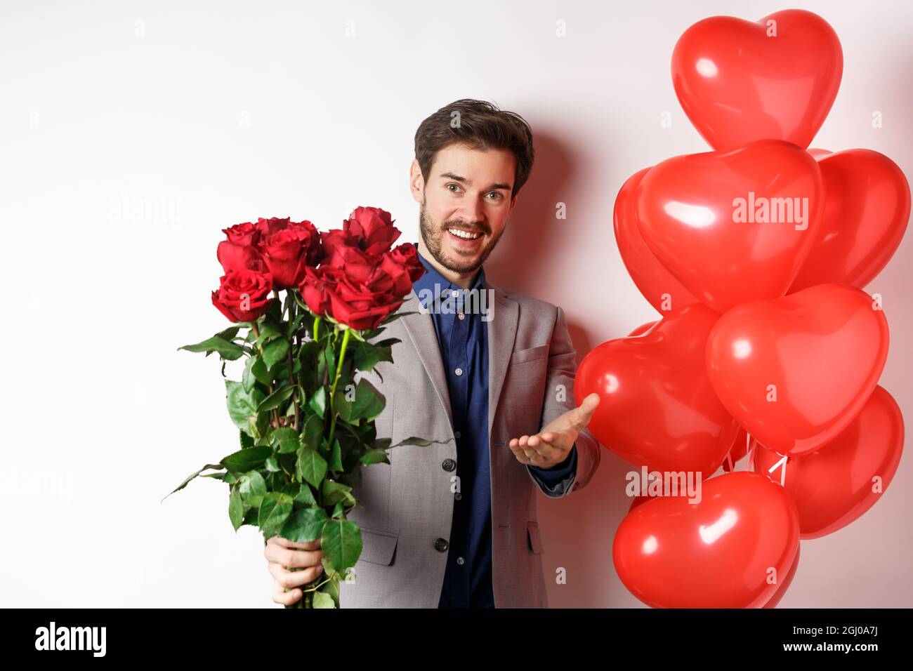 Romantic guy in suit saying happy Valentines day, giving red roses to ...