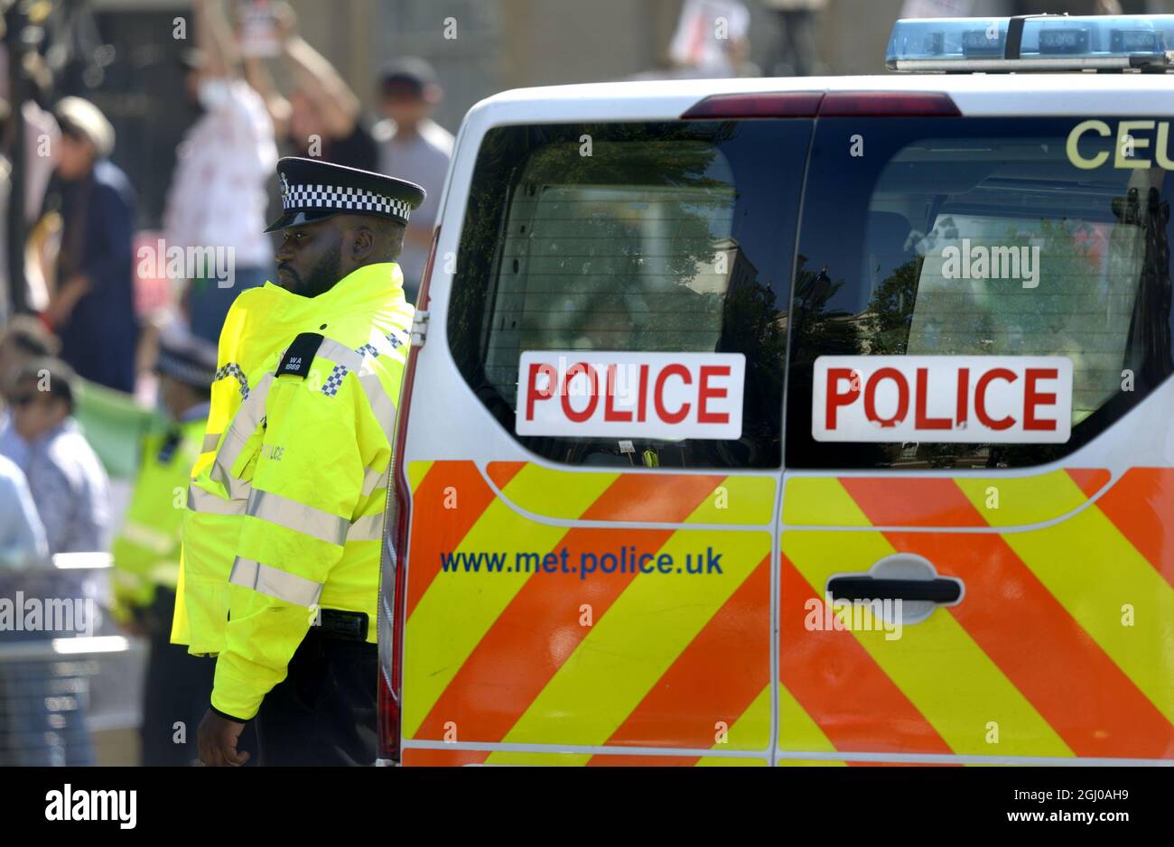 London, England, UK. Black police officer standing beside a police van during a protest in Westminster Stock Photo
