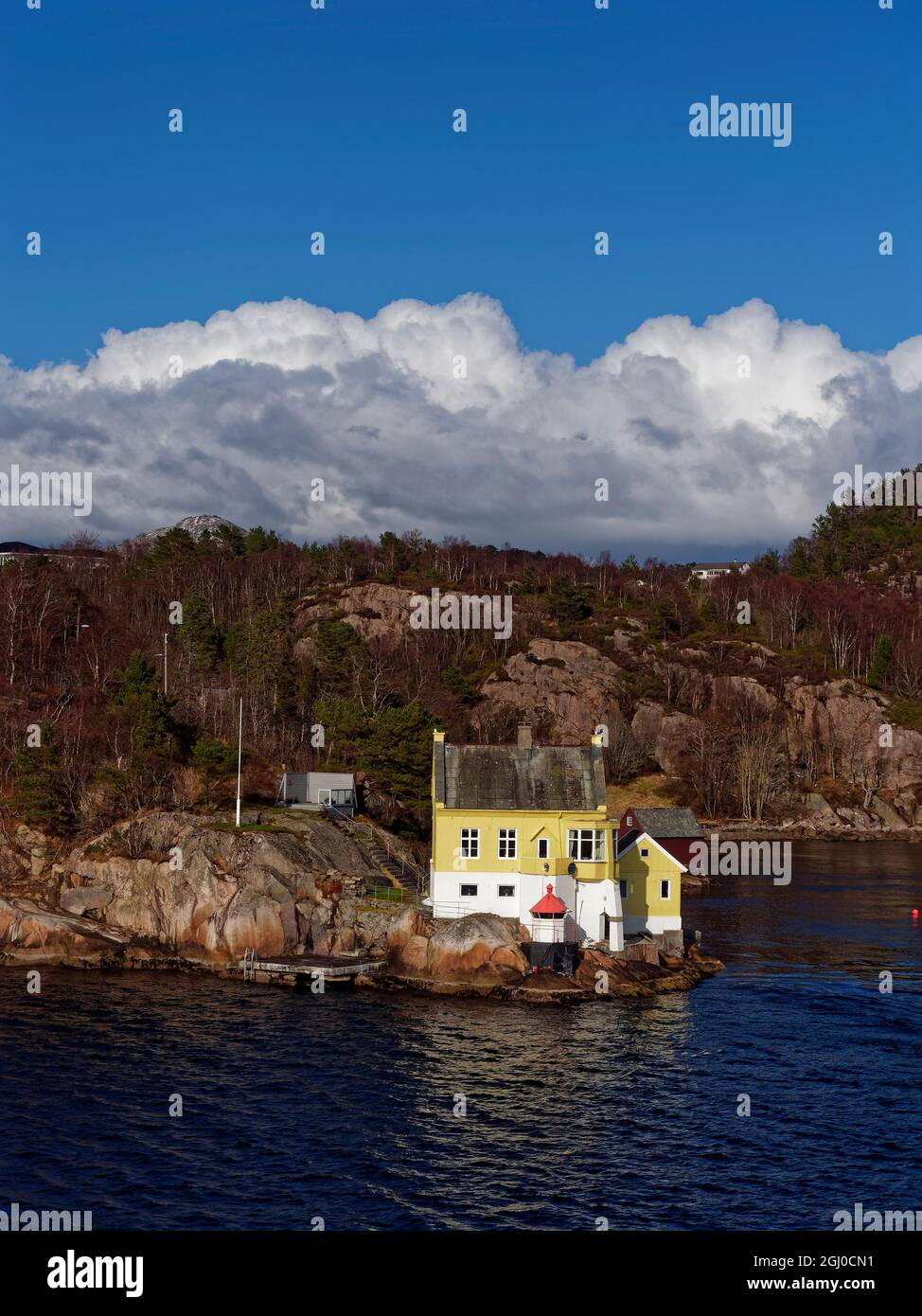 A Traditional wooden Norwegian House set close to the Waters edge next to a Navigational Marker and Light, close to the Port of Bergen. Stock Photo