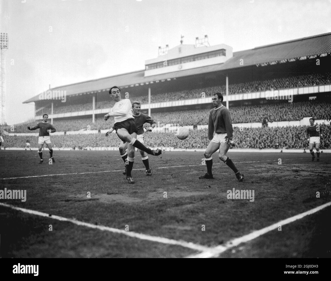 Tottenham Hotspur V Everton Spurs new centre forward Alan Gilzean (left) kicks the ball during the match at White Hart Lane. Also shown are Everton players, left back Colin Harvey and right half Gabriel. London - 19th December 1964. Stock Photo