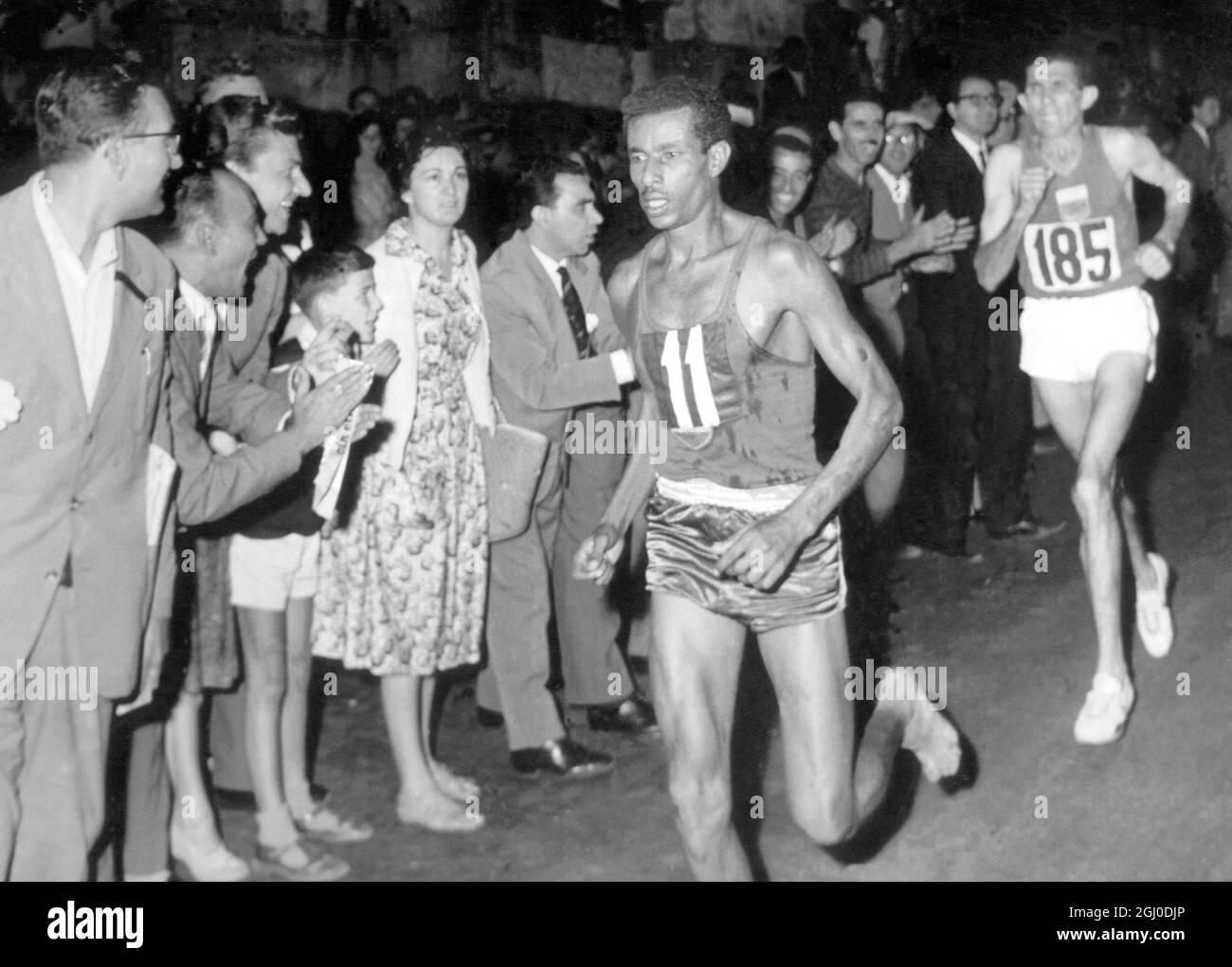 To the cheers of a huge crowd in Rome, Bikila Abebe of Ethopia (11) runs barefooted up to the finishing line to win the 26 mile marathon of the 1960 Olympic games, in a record time of 2 hours 15 minutes 16.2 seconds. He was closely followed by Abdesian Rhadi of Morocco (185). The two had been the only ones in the race with a chance of winning on the halfway mark 10th September 1960. Stock Photo