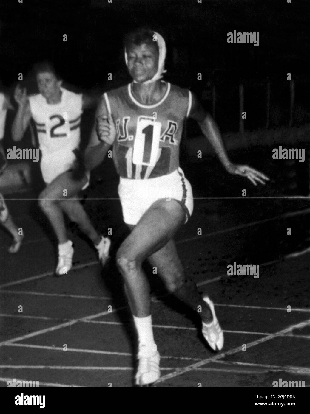 Wilma Rudolph of USA wearing a head scarf as protection against heavy rain, wins the 100 yards event at the athletics meeting between the British Empire and Commonwealth and the United States Olympic team. Wilma won three gold medals at the Olympic Games in Rome, two individual, and one in a relay race. London - 14th September 1960. Stock Photo