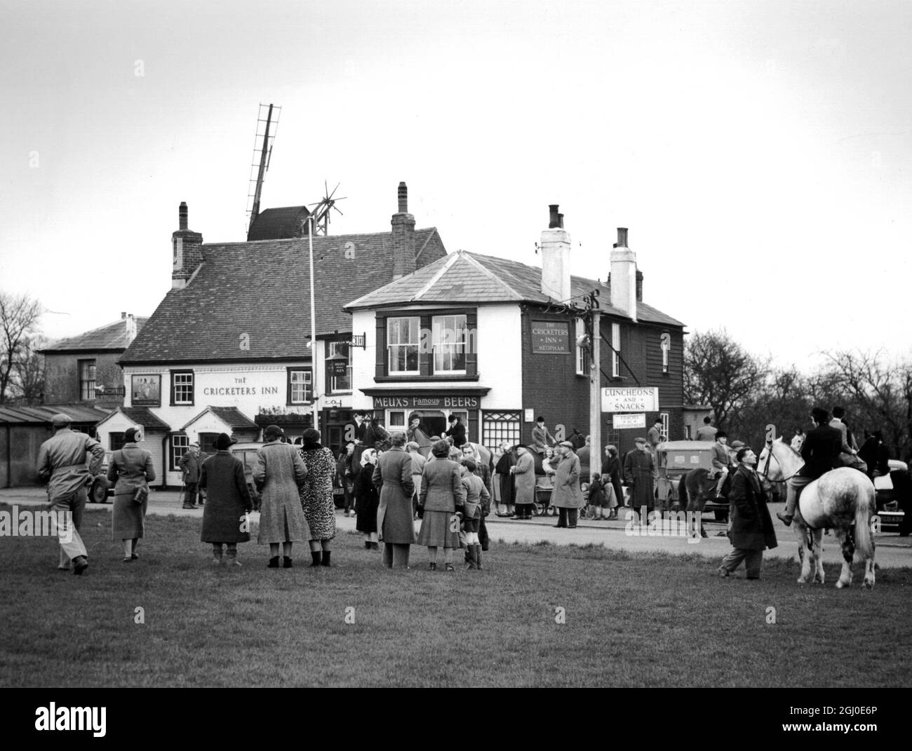 They met on the cricket green outside the Cricketers Inn Meopham, Kent - but horses weren't allowed on the green itself. The meet was that of the West Kent Hunt (and Pony Club). The derelict windmill behind the inn is a landmark. 19th January 1954. Stock Photo