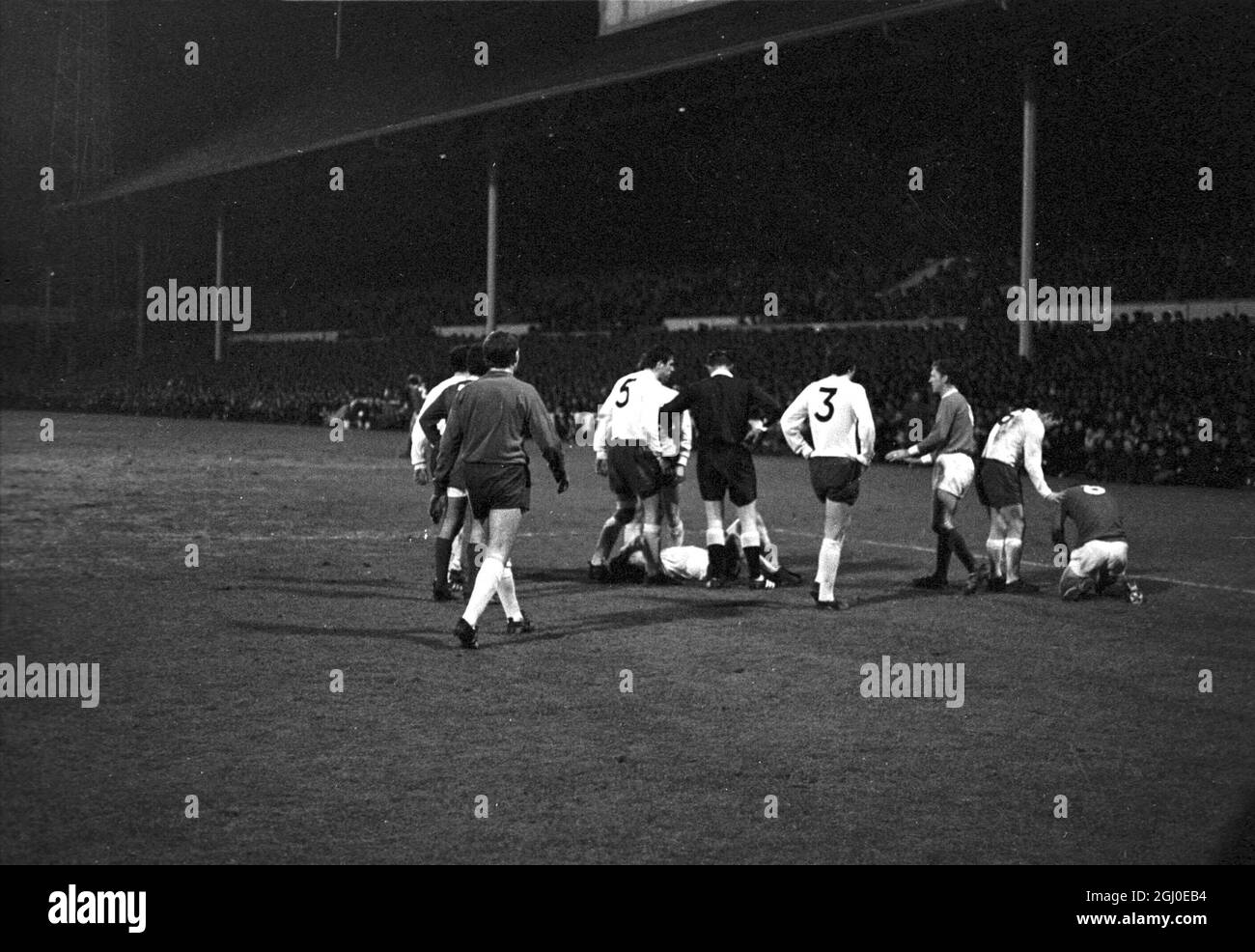 Tottenham Hotspur v Manchester United Two players lay on the White Hart Lane pitch after a flare up in the FA Cup third round replay. Tottenham Hotspur skipper and left back Dave Mackay (No.6) points to Manchester United inside-right Brian Kidd, holding his head in pain after his punch up with Tottenham right back Kinnear (on ground left) which ended in the two men being sent off. Players surrounding the Spurs player are (from left) Alan Gilzean, George Best, Alan Mullery, Mike England, Pat Jennings, left winger Beal, and Cyril Knowles. Spurs won the game 1-0 after extra time. 31st January 196 Stock Photo