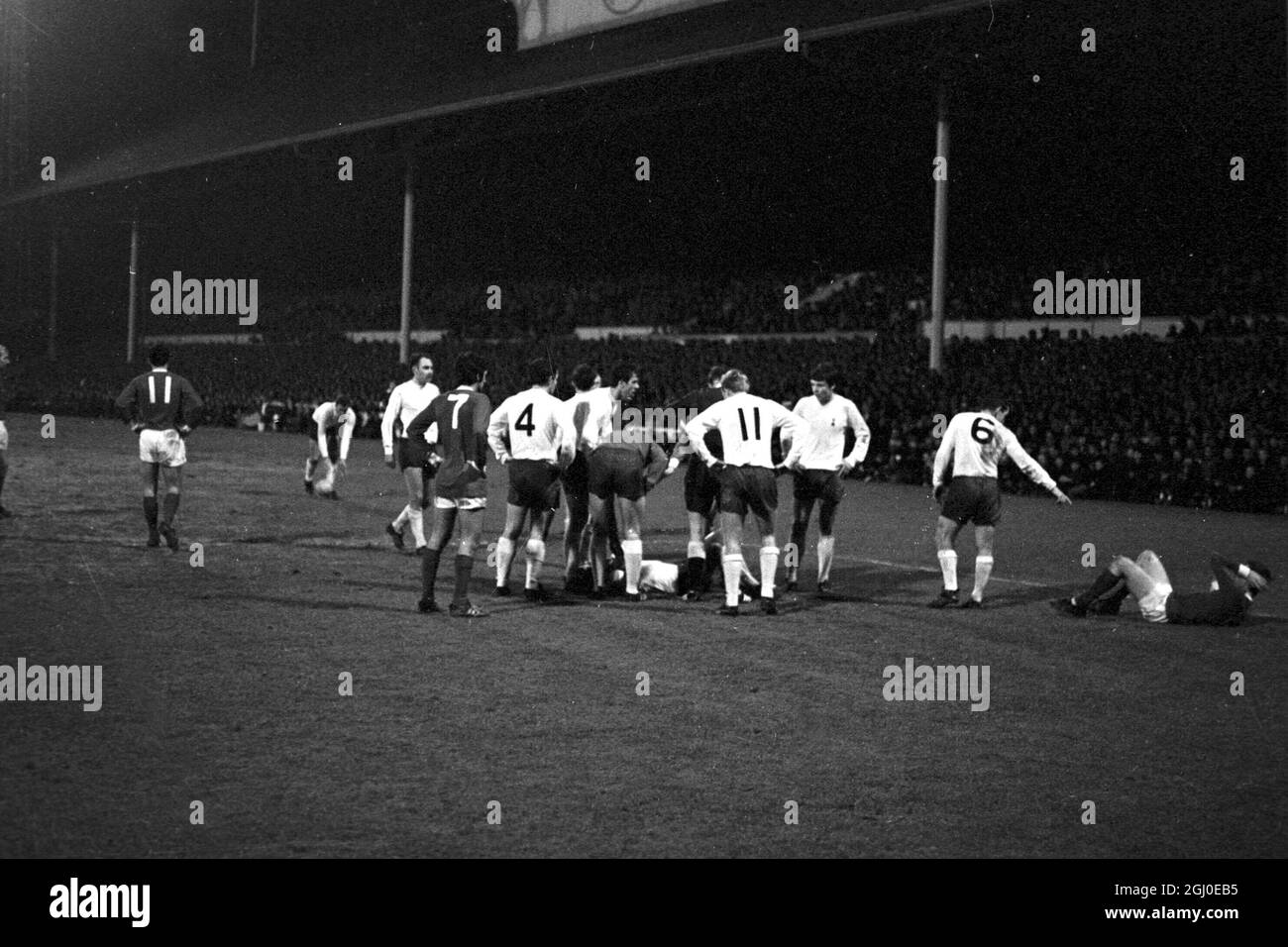 Tottenham Hotspur v Manchester United Two players lay on the White Hart Lane pitch after a flare up in the FA Cup third round replay. Tottenham Hotspur skipper and left back Dave Mackay (No.6) points to Manchester United inside-right Brian Kidd, holding his head in pain after his punch up with Tottenham right back Kinnear (on ground left) which ended in the two men being sent off. Players surrounding the Spurs player are (from left) Alan Gilzean, George Best, Alan Mullery, Mike England, Pat Jennings, left winger Beal, and Cyril Knowles. Spurs won the game 1-0 after extra time. 31st January 196 Stock Photo