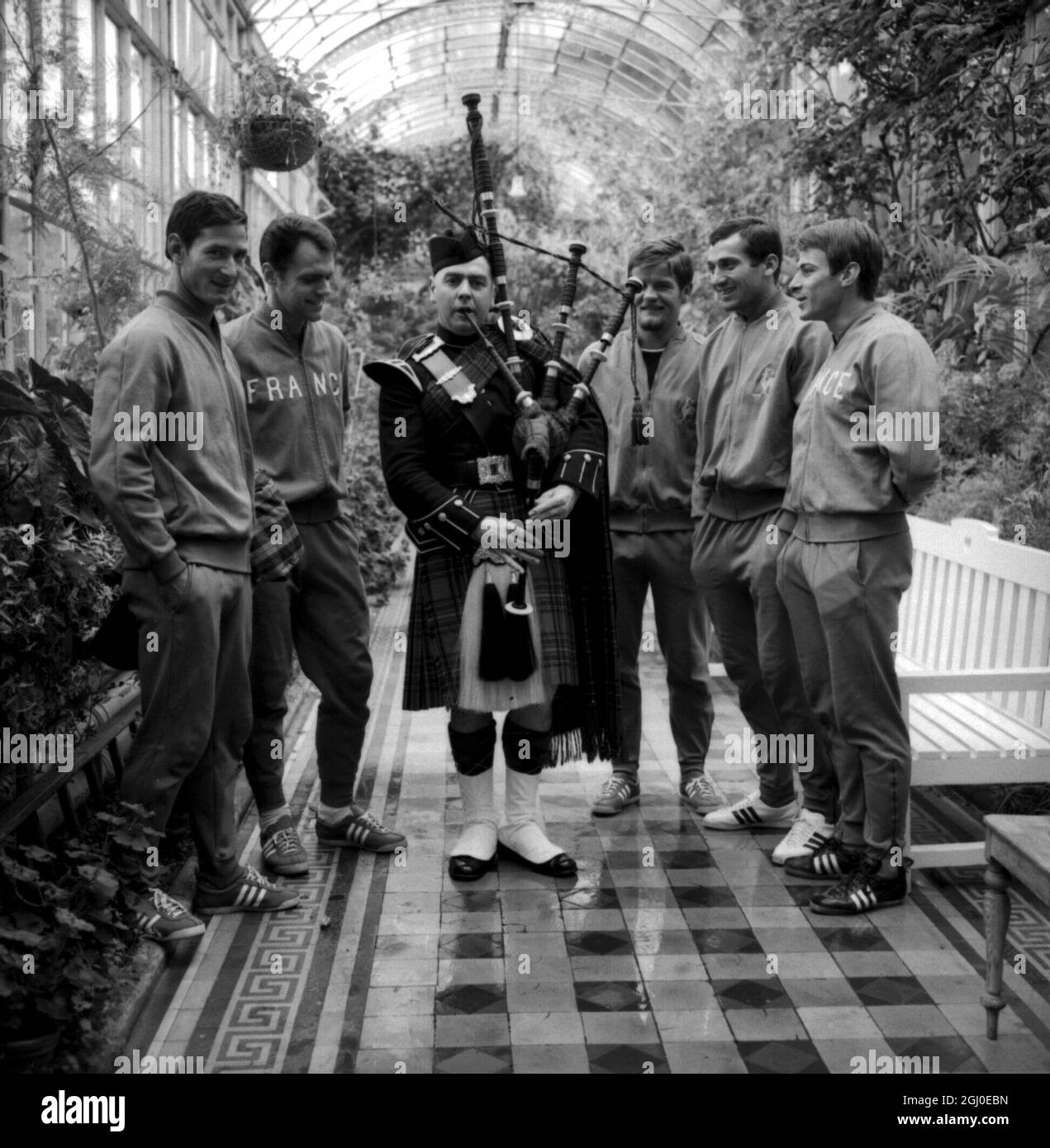 Scotland has had links with France since the time of the ill-fated Mary, Queen of Scots, and here cementing the friendship between the two countries, is resident piper of Peebles Hotel, Scotland, Alexander Brown, wearing Royal Stewart tartan, playing his bagpipes for members of the French football team, currently in the UK for next month's World Cup Games. The players are from left to right, Marcel (captain); Lucien Muller; Robert Budzinski (back); Aubour (goalkeeper) and Philippe Gondet (forward). 23rd June 1966. Stock Photo