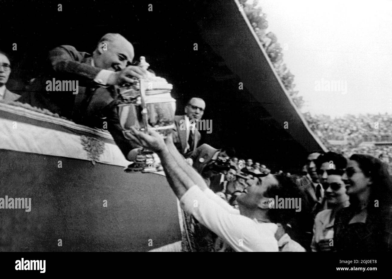 65,000 soccer fans saw the Seville Soccer Club win the Cup of Spain by defeating the Celta de Vigo Club 4-1 at the Chamartin Stadium. General Franco who attended the match with his wife, is seen presenting the winning cup to Josquin, captain of the Seville Soccer Club after the match. 9th July 1948. Stock Photo