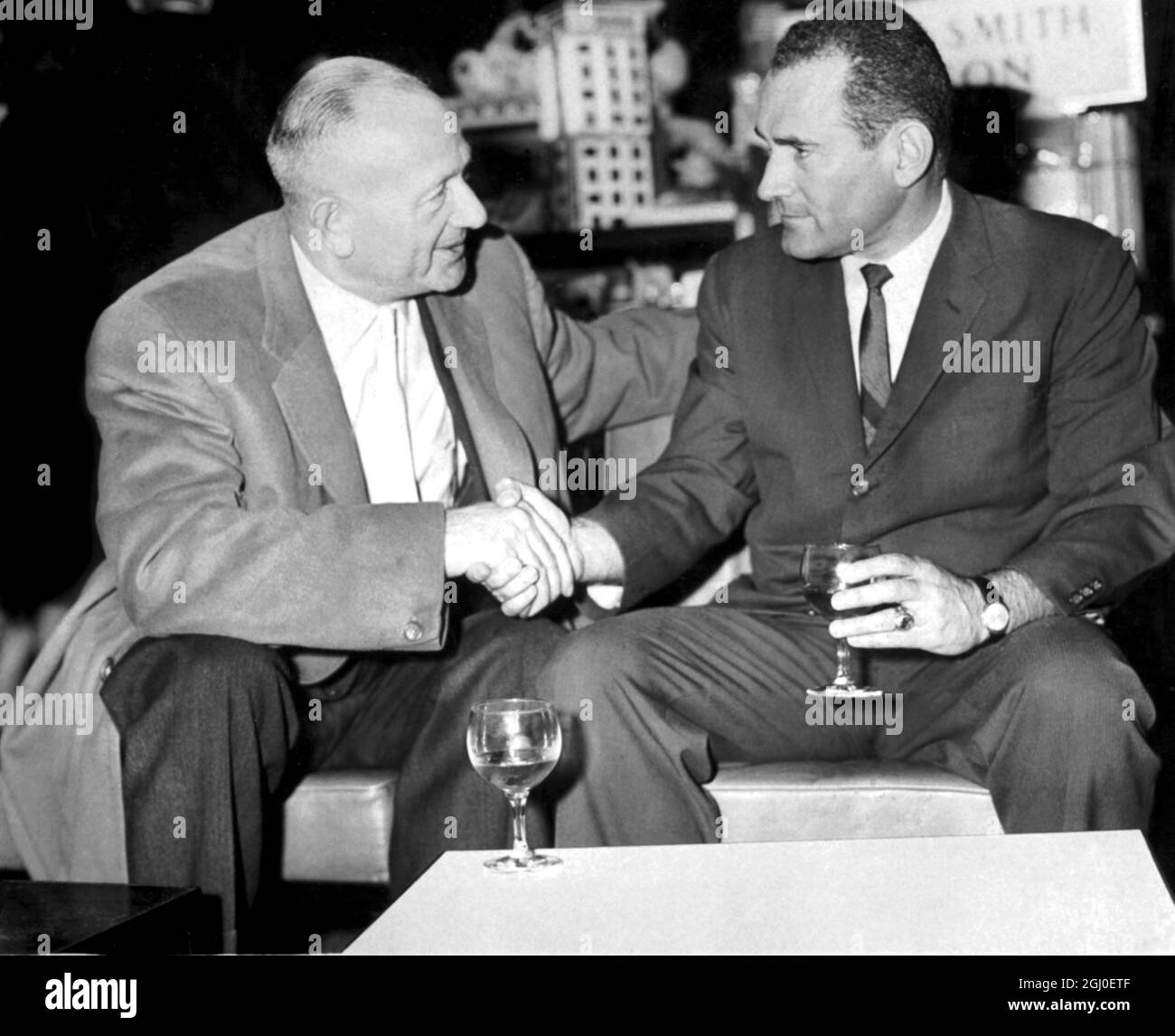 Jack Solomons the British boxing promoter, left and Gil Clancy shake hands at London Airport. 18th October 1962. Stock Photo