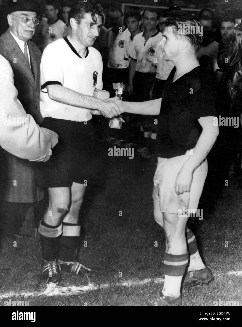 1954 World Cup Final West Germany v Hungary Hungarian team captain Ferenc Puskas (right) congratulates German captain Fritz Walter, who happily holds the cup, after Germany had defeated Hungary 3-2 in the final of the 1954 World Cup. On the left is former FIFA President Jules Rimet. 4th July 1954. Stock Photo