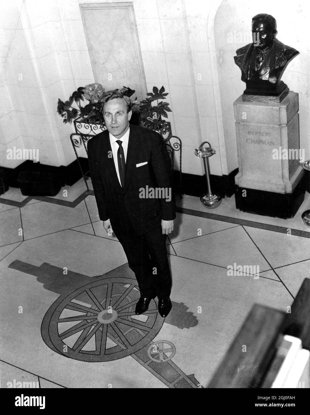 Billy Wright stands to attention on the Gunners cannon in the entrance hall of Highbury Stadium where he took over as Arsenal manager today. 2nd May 1962. Stock Photo