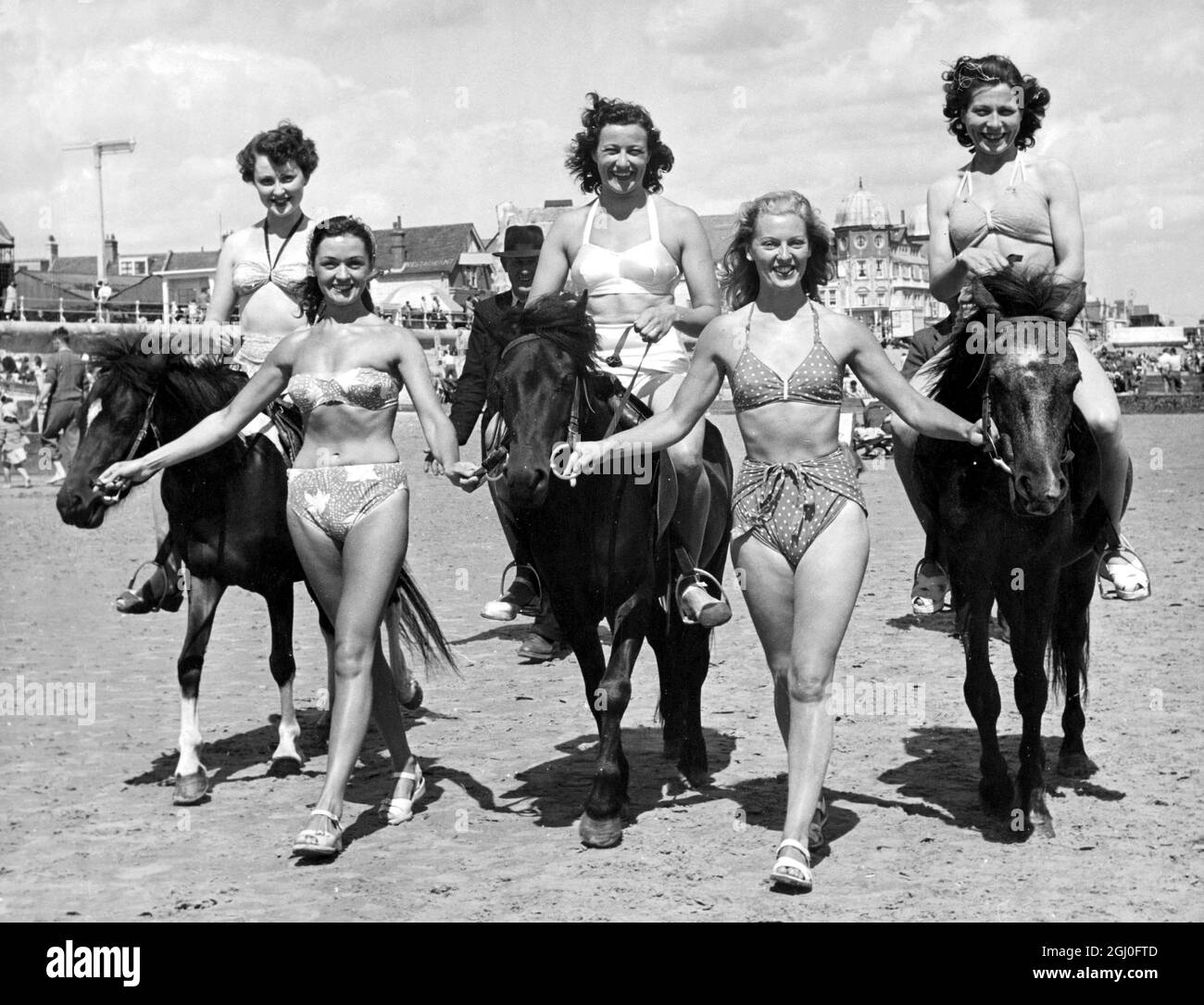 Glorious Goodwood? No! Bouncing Bognor Regis It might be the parade round the track before the start of a big race if the mounts had less mane and riders more clothes. In actual fact the girls running off the pony stakes on the beach at bognor. Trophy is the celibrated ''ice cream cone'', an award popular at seaside resorts at this time of year. Riding habits are swim suits in this sport. July 29th 1950 Stock Photo