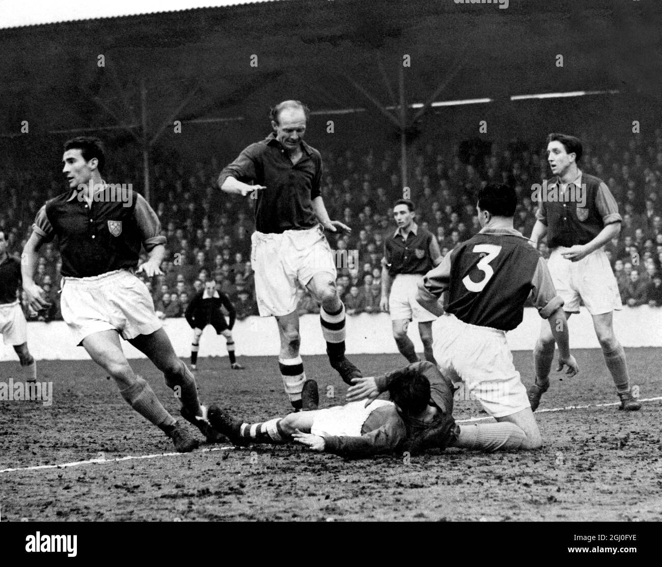 West Ham v Nottingham Forest. A scramble around the West Ham goal during the match at Upton Park. On the left is Malcolm Allison, the West Ham centre half, whilst Collingdridge, Forest centre-forward is about to jump over Moore, the Forest outside-right (on ground). Kneeling is Kentwell (No.3), the West Ham left-back. February 20th 1954 Stock Photo