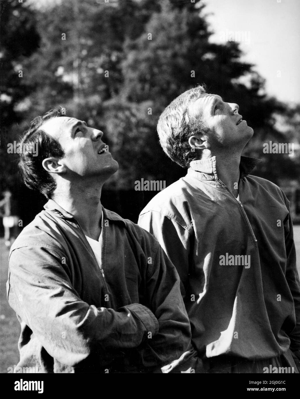 England players, Jimmy Greaves (left) and Bobby Moore (right), are distracted by an aircraft during their training session at Roehampton, Surrey. They are competing against The Rest Of The World at Wembley on the 23rd October 1963. 22nd October 1963 Stock Photo