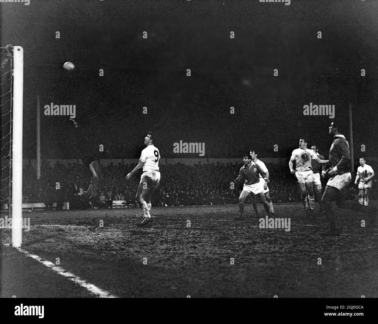 1962 European Cup Semi Final Tottenham Hotspur v Benfica Spurs' left-half Mackay (with arm outstretched on right) sends the ball towards the goal but it rebounds off the crossbar, during the European Cup Semi-final (2nd leg) at White Hart Lane. Standing behind one of the defenders (centre right) is Spurs' inside-left Jimmy Greaves and in front of the goalmouth is centre-forward, Bobby Smith (No.9). 6th April 1962 Stock Photo