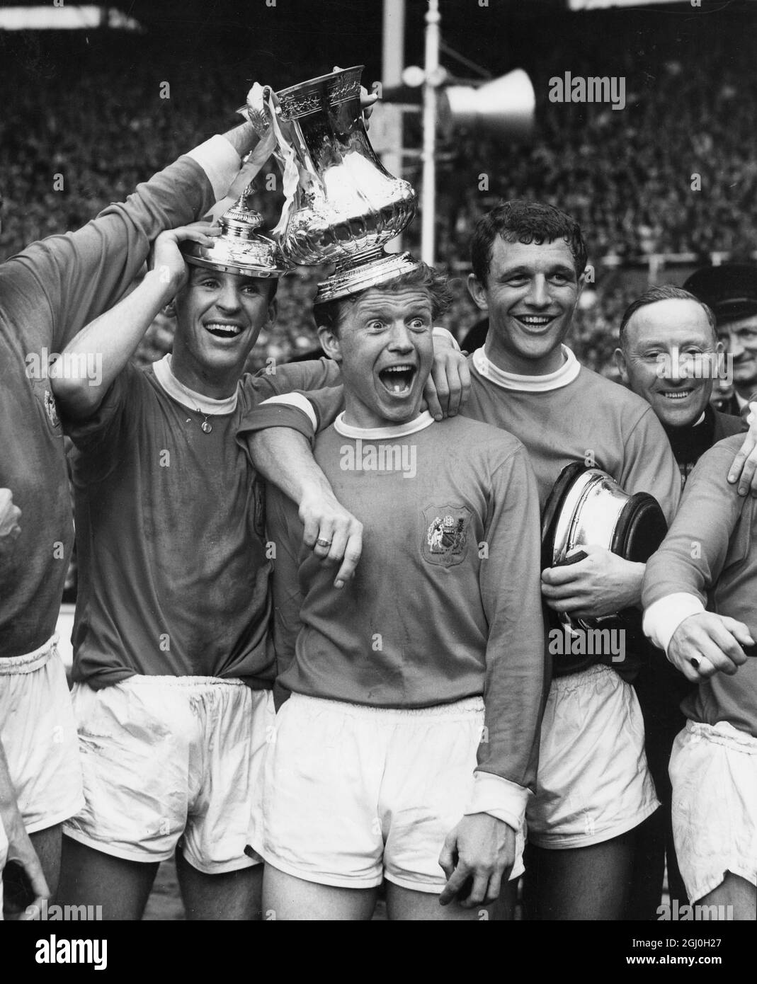 25th May 1963: The FA cup final at Wembley Stadium. Manchester United (3) versus Leicester City (1). Photo shows: The cup winners' feelings are expressed here by (l-r) Pat Crerand, Albert Quixall and David Herd, who scored two of United's goals. : The FA cup final at Wembley Stadium. Manchester United (3) versus Leicester City (1). Photo shows: Manchester United centre-forward, David Herd (dark shirt, second from the right), the scorer gives a cry of triumph as the ball crosses the City goalline for their second goal. Stock Photo