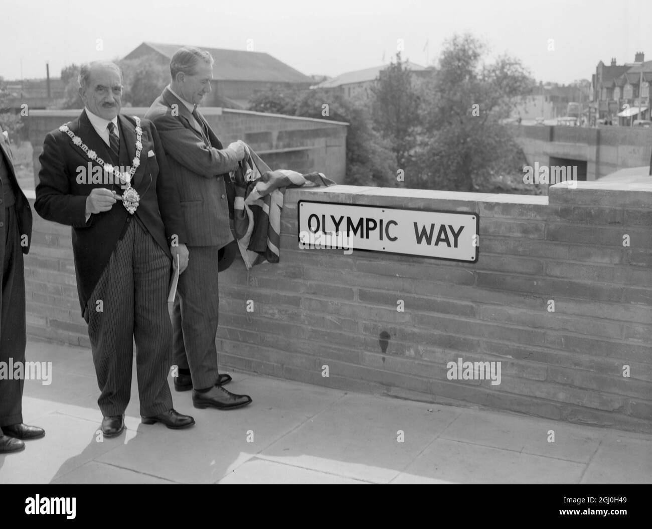 The Minister of Transport Mr Alfred Barnes performed the opening ceremony for the new road to Wembley Stadium from Wembley Park Station and named it Olympic Way to perpetuate the staging of the Olympic Games at Wembley. Picture shows Mr Alfred Barnes unveils the name plate Olympic Way. The Mayor of Wembley is on the left. 6th July 1948 Stock Photo