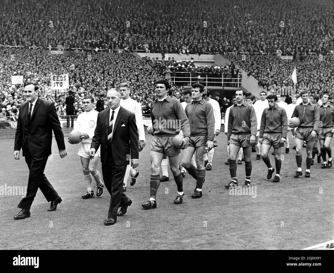 Don Revie (left) and Bill Shankly, managers of Leeds United and Liverpool lead their teams out onto the famous Wembley turf before the start of the 1965 FA Cup Final. Leeds players following behind include captain Bobby Collins and goalkeeper Gareth Sprake. Liverpool players behind Shankly are captain Ron Yeats, goalkeeper Tommy Lawrence, Gerry Byrne, Ian Callaghan, Willie Stevenson and Peter Thompson. 3rd May 1965. Stock Photo