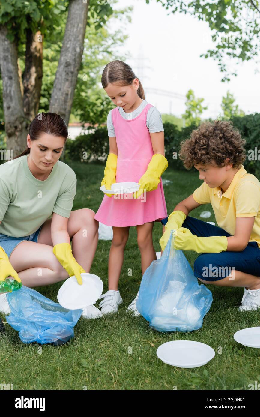 Mother and children picking up trash on lawn Stock Photo Alamy