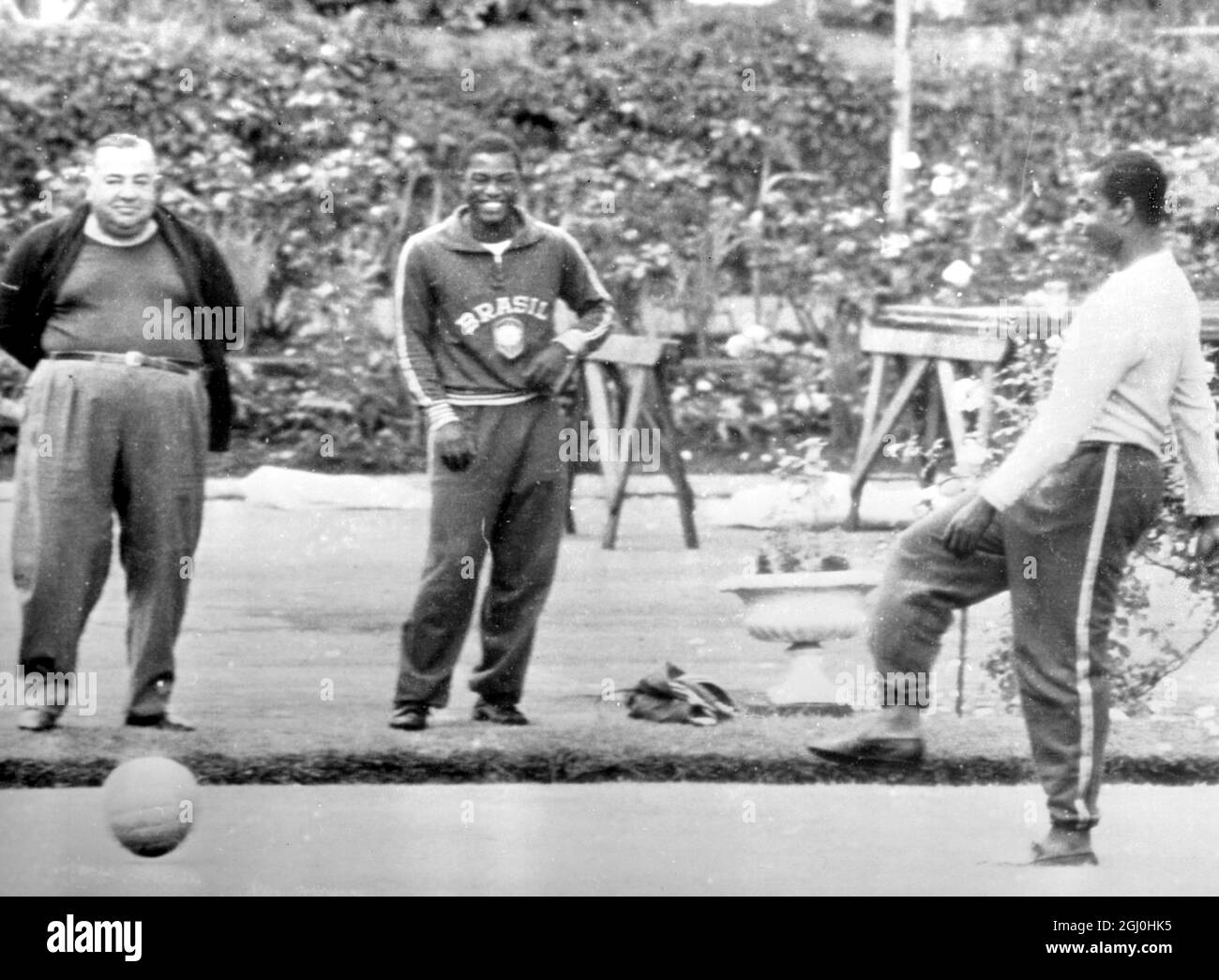 Vincente Feola (left), manager of the 1966 Brazilian World Cup Football team, watches as two of his players, Fidelis (centre), and Lima have a workout on the bowling green of the team's hotel at Lymm, Cheshire in England. 11th July 1966. Stock Photo