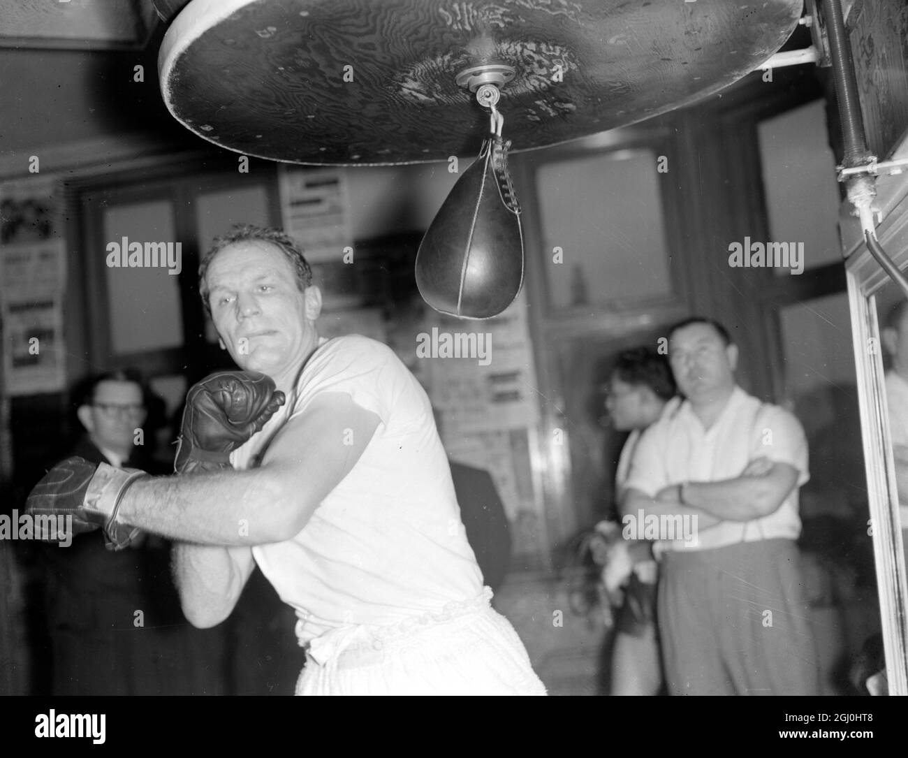London: A grin faced Henry Cooper, British and Empire Heavyweight champion , puts in some practice on the high speed punch ball in readiness for his fight with American Zoro Folley at Wembley on Tuesday December 5th. Cooper has been training hard for contest for if he wins he hopes to have a crack at World Championship holder Floyd Paterson. 30 November 1961 Stock Photo