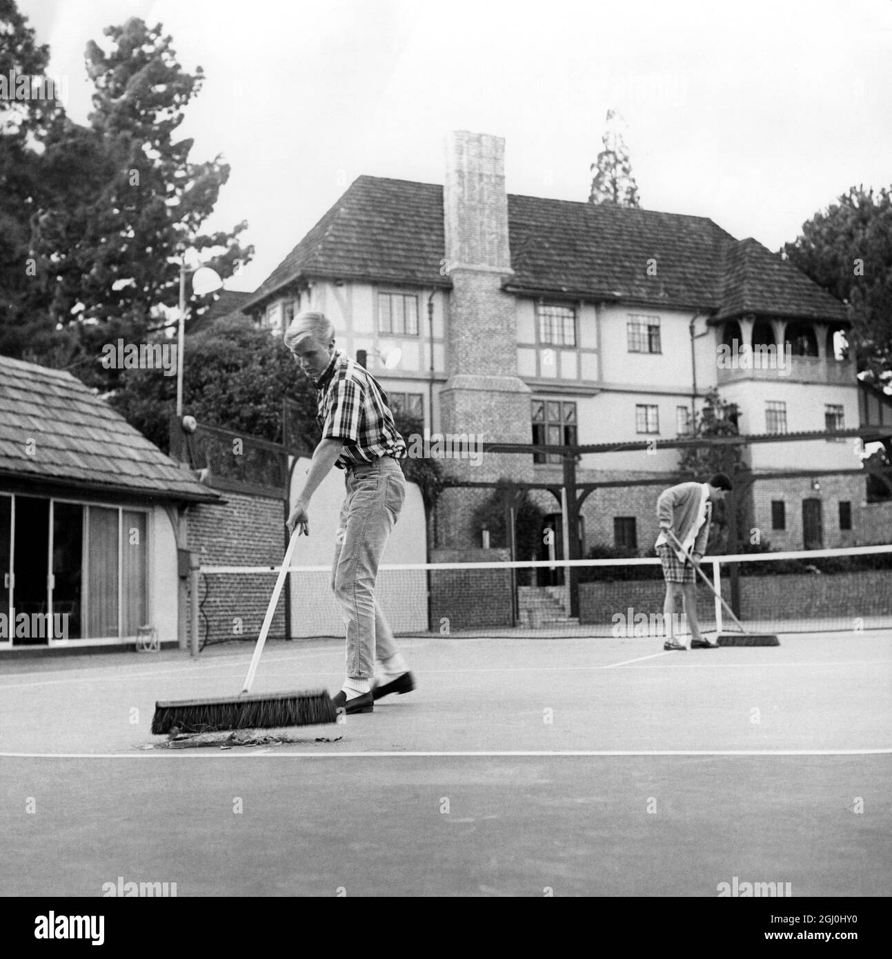Boys sweeping the clay court at the tennis club Stock Photo Alamy