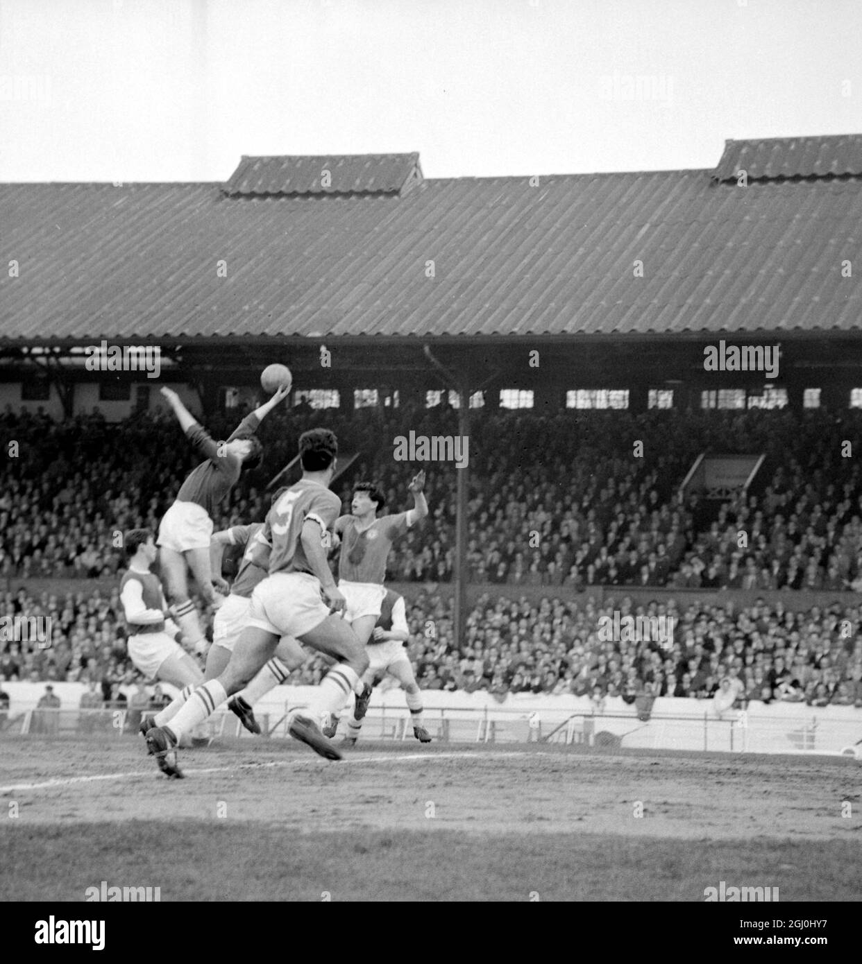 London: Chelsea goalie Bonetti leaps to save the ball during this afternoon's soccer game when Chelsea met Arsenal at Stamford bridge. Also shown is Chelsea centre-half Scott (No 5) with back to the camera who partly hides Chelsea's right-back J. Sillet. 15 April 1961 Stock Photo