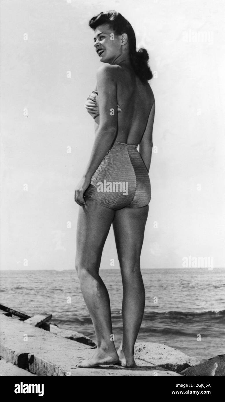 Backless and Strapless... The latest in swimsuits from Hollywood is this smart strapless and backless creation. The clamped on bra has back straps for high diving the trunk is shirred with lastex thread in back for form fitting beauty. 1950s Stock Photo