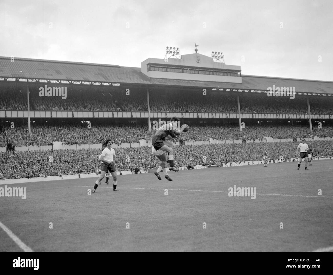Tottenham, Middlesex: Tottenham Hotspurs' Goal keeper Brown (forground) Grabs the ball despite being heavily pressed by Everton Centre - Forward Harris at Spurs' home ground here today -- First Day of the football season. 20 August 1960 Stock Photo
