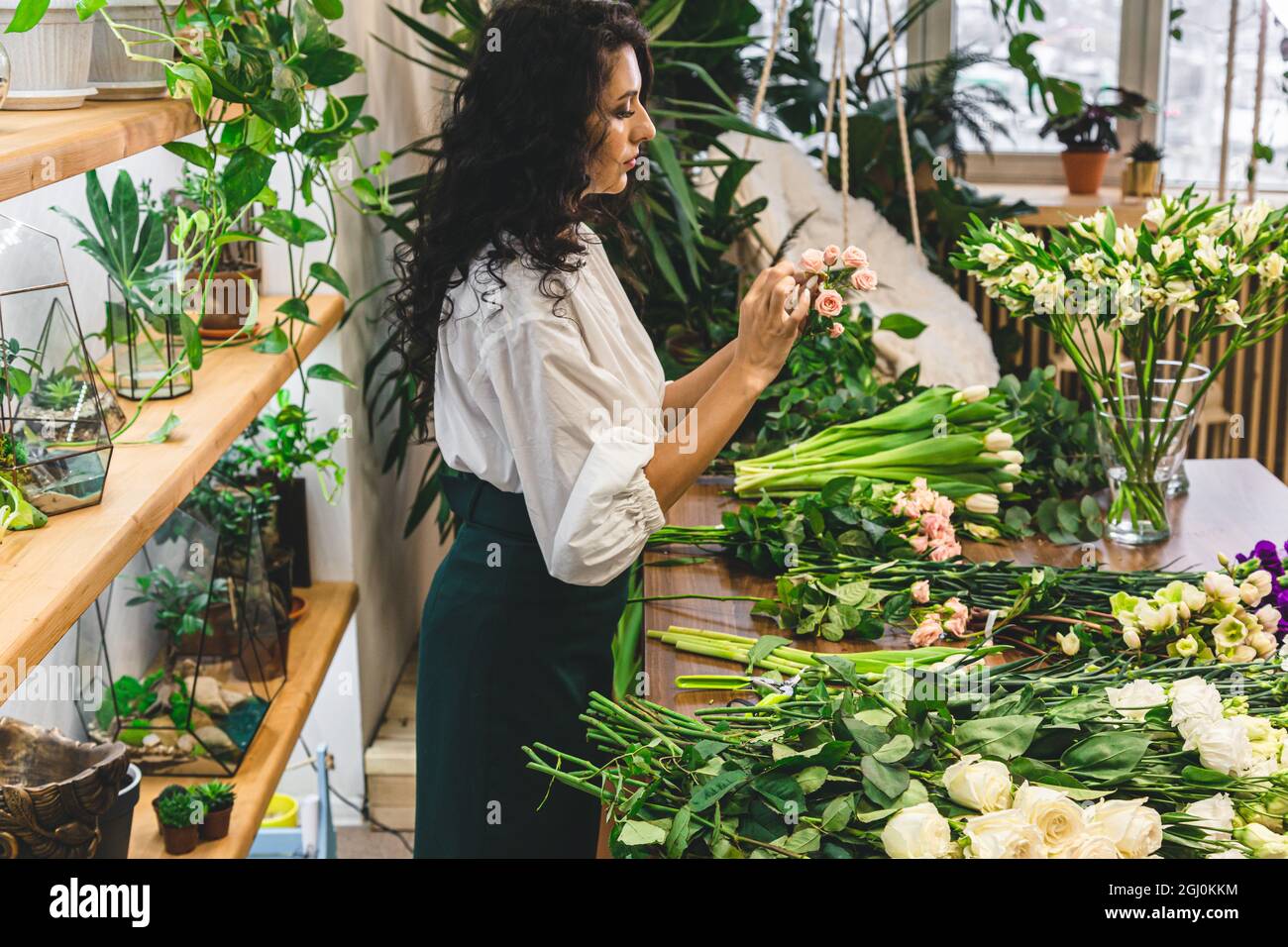 Attractive young woman florist is working in a flower shop Stock Photo ...