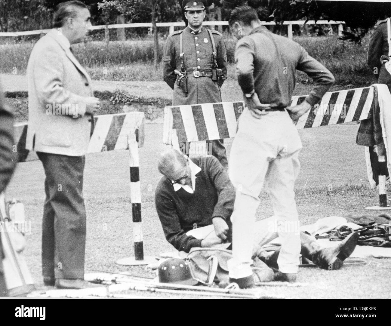 San Diego, Chile: H.R.H. Duke Of Edinburgh (seated on ground) puts on his polo kit here recently as he prepares to play a friendly game of his favourite sport, Polo. With him is another unidentified player with a South African journalist at left and policemen looking on behind the barriers. 12 March 1962 Stock Photo