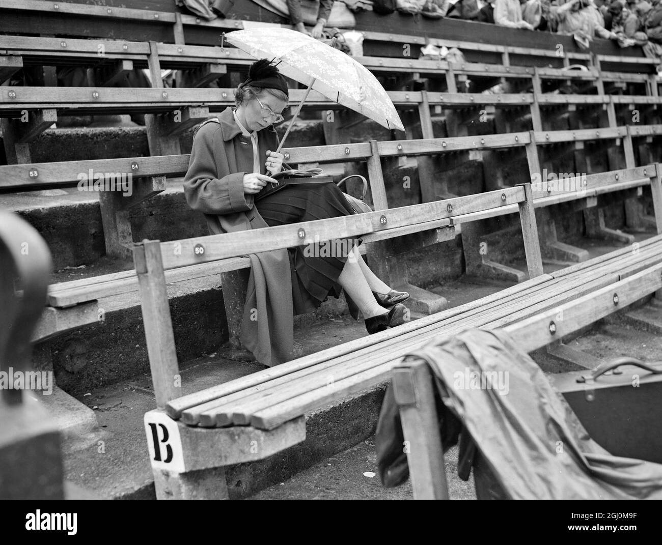 Rain stops play at Wimbledon spectators are shown bearing umbrellas and head covering awaiting break in weather. 3 July 1952 Stock Photo