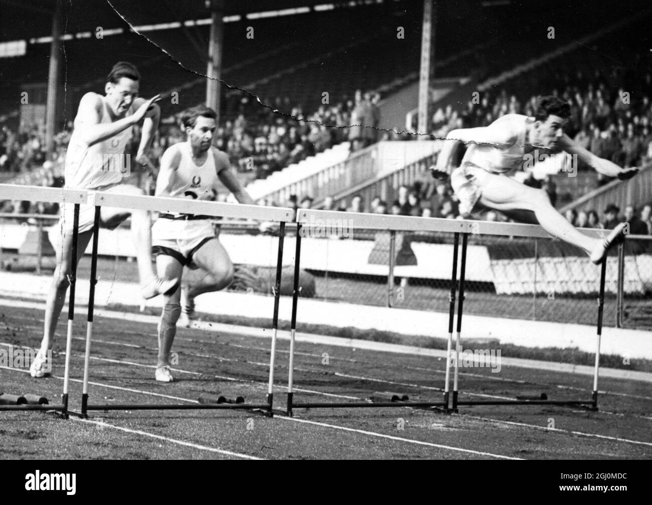 Oxford and Cambridge M . C . Robinson ( right ) , Cambridge leading R . P . Van Rossum ( centre ) Oxford and D . A . Rutherford ( left ) Cambridge in 120 yards High Hurdles in Inter University Sports at White City London 22 March 1958 Stock Photo
