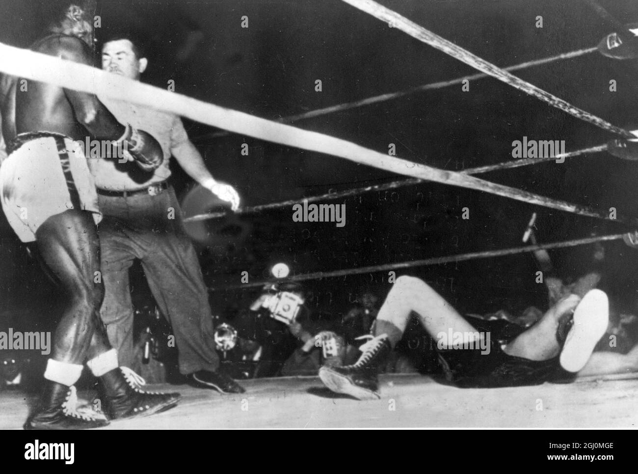 Wrigley Field , Los Angeles . Hogan ' Kid ' Bassey of Nigeria the World Featherweight Champion is restrained by referee after the former had floored Ricardo ' Little Bird ' of Liverpool in the third round . The count ended with only seconds of the round to go . 3 April 1958 Stock Photo