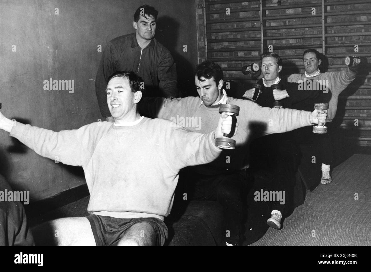 Tottenham Hotspur FC , now back in training with new team member Jimmy Greaves , after his recent transfer from Milan . Training under the watchfull eye of weight lifting expert Bill Watson , from front ; team Captain , Danny Blanchflower , the new club member Jimmy Greaves , Peter Baker and Les Allen . 8th December 1961 Stock Photo