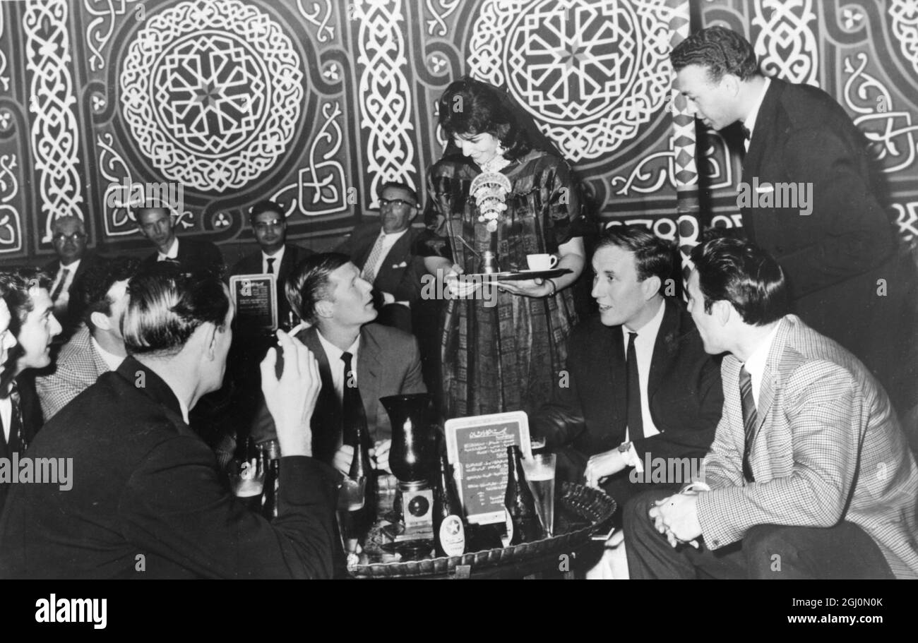 A waitress talking to footballers , Jimmy Greaves and Peter Baker and other members of the Spurs Team at the Hilton Hotel in Cairo , Egypt . Spurs will be playing Zamelek , the top Egyptian team in Cairo . 13th November 1962 Stock Photo