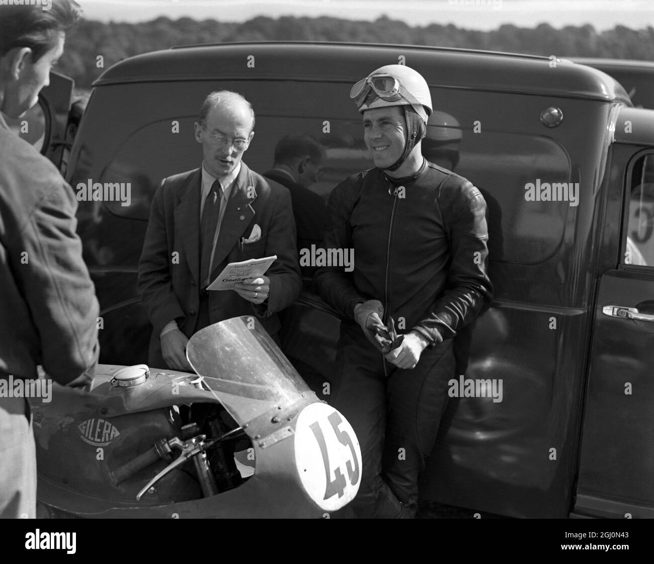 Geoff Duke , British world road racing motorcycle champion , relaxes during practise at the Brands Hatch racing curcuit in Kent . 24th September 1955 Stock Photo